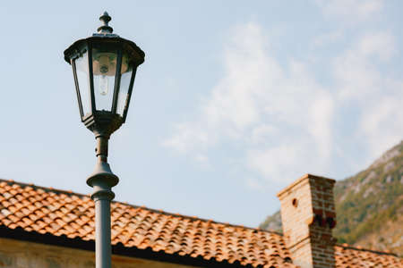 High street lamp at the level of the roof of the house against the background of mountains and sky.の写真素材