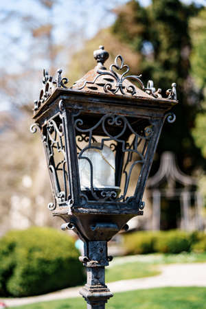 Close-up of a street lamp with a metal body with patterns in the park.