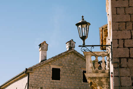 Street lamp on the wall of the building near the balcony against the blue sky.の写真素材
