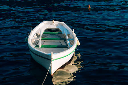 Fishing white wooden boat with oars on the blue water of the Bay of Kotor in Montenegro.の写真素材
