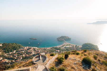 The bride and groom embrace on the observation deck in front of them a panoramic view of the sea and the island of Sveti Stefanの写真素材