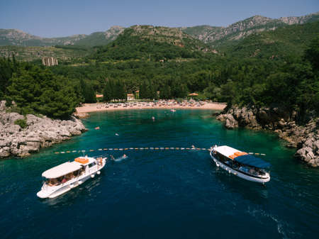 Two pleasure tourist ships moored near the beach in Montenegro, near an old villa.の写真素材