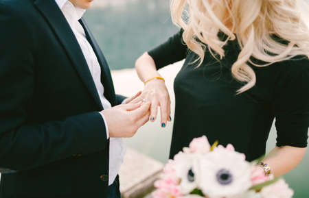 Man is putting an engagement ring on a womans finger after she accepts his proposal