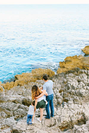 Family of four are looking at the sea on a rocky beach in Montenegroの写真素材