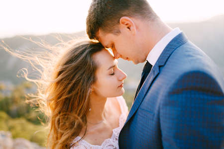 The bride and groom tenderly embrace on Mount Lovcen, the groom leaned his nose against the brides foreheadの写真素材