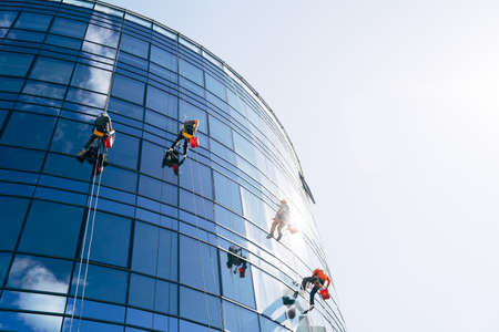 Industrial climbers cleaning blue windows outside building.の写真素材