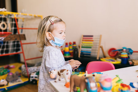 Budva, Montenegro - 17 march 2021: Child girl in a protective mask playing in kindergarten.のeditorial素材