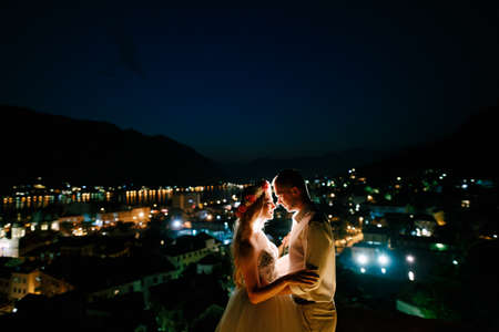 The bride and groom embrace at sunset on the observation deck above the old town of Kotor, close-upの写真素材