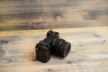 Budva, Montenegro - 15 march 2021: Sony a6300 camera with 16-50mm lens on wooden background texture. Sony mirrorless camera.のeditorial素材