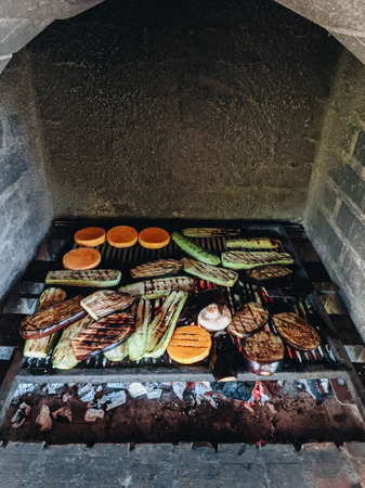 Grilled vegetables. Courgette, mushrooms and pumpkin on a metal grill over red coals.