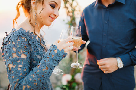 Bride and groom drink champagne from glasses near the wedding arch during the wedding ceremonyの写真素材