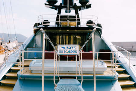 Stern trawl of a beautiful motor white yacht with a wooden ladder. Inscription: PRIVATE No Boarding. Close-upの写真素材