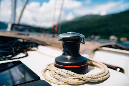 Black halyard winch with a variegated cable against the backdrop of a mountain landscape