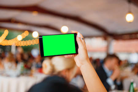 Womans hand with a smartphone photographs the party. Blank screenの写真素材