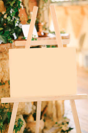 White easel stands against the background of a column entwined with green ivyの写真素材