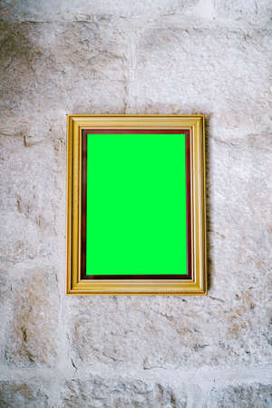 Blank picture in wooden frame hanging on stone wallの写真素材