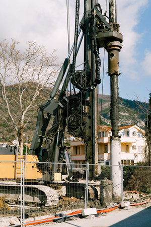 Crawler tractor with a drilling rig works behind a fence against the backdrop of a houseの写真素材