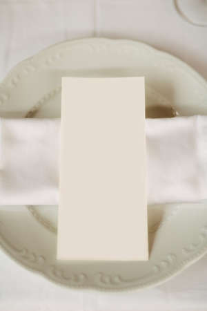 Blank card lies crosswise on a white cloth napkin on a plate