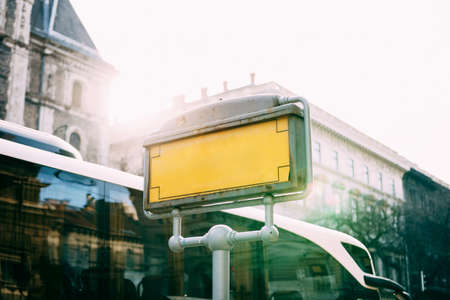 Empty signboard at a bus stop with houses and a passing white bus in the backgroundの写真素材