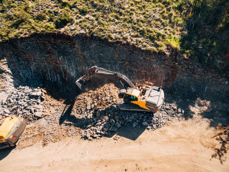 Yellow tracked tractor is working on the extraction of rock. View from above