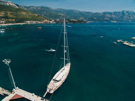 White sailing yacht on the pier near the city of Budva Montenegro against the backdrop of mountains