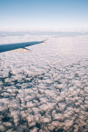 View from the airplane window on white cumulus clouds belowの写真素材