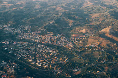 View from the airplane window of the green mountain ranges and the city in the Tuscany region