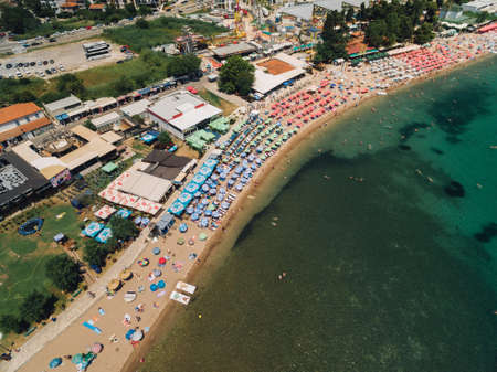View of the Budva beach against the backdrop of buildings, greenery and the sea. The beach has sun...
