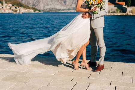 Legs of the bride and groom hugging on the pier in the Bay of Kotor behind them the old town of Perastの写真素材