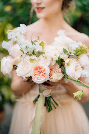 Bride in a beautiful dress holds a bouquet of pink flowers in her handsの写真素材