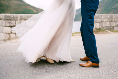 Groom and bride stand against the background of the stone wall