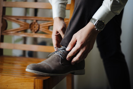 Groom straightens the laced laces with his foot on the chairの写真素材