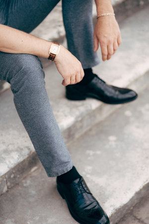 Groom is sitting on the steps in a gray suit and black shoes. Legs close upの写真素材