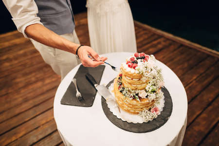 The groom takes a piece of cake with a fork to give to his bride at a wedding banquetの写真素材