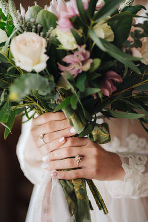 Bride in a white wedding dress is holding a beautiful wedding bouquet. Half portraitの写真素材