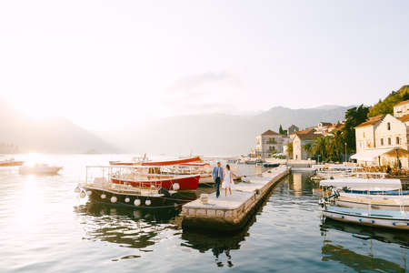 Panorama of the coast of the town of Perast Montenegro. Groom and bride walk along the pier holding handsの写真素材