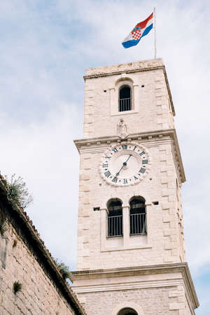 Bell tower with the clock of the Church of St. John in Sibenik against the blue skyの写真素材