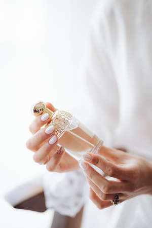 Bride in a white lace robe holds a bottle of perfumeの写真素材