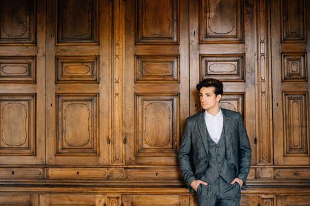 Groom stands with his hands in his pockets on the background of a wooden wall. Lake Comoの写真素材