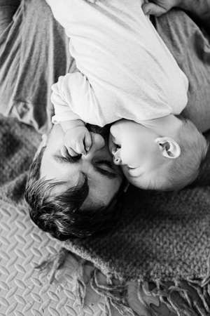 Tiny baby lies on dads chest with a hand on his face. Black and white photo. Close-upの写真素材