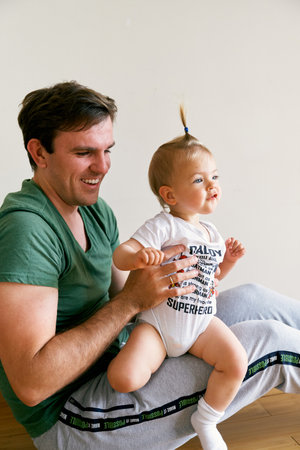 Smiling dad holding a little toddler with a ponytail on his lap