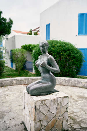 Budva, Montenegro - 08.04.2021: Statue of a seated girl in a tiled pool against the backdrop of a buildingのeditorial素材