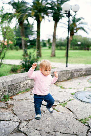 Little girl walks on paving slabs against the background of treesの写真素材