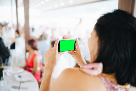 Woman at a wedding banquet filming a party on a smartphone, close-up