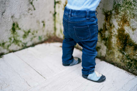 Babys feet on the paving slabs near the stone fence. Close-up