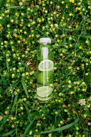 Bottle of water with lemon and lime lies among yellow wildflowersの写真素材