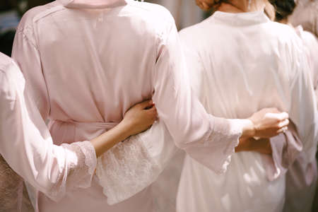 Bridesmaids in robes are hugging each other. Back viewの写真素材
