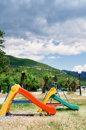 Children slides on the playground against the backdrop of green trees and mountains
