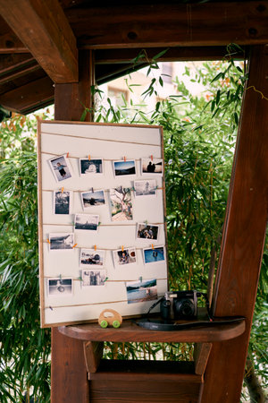 Photos are hanging on the board attached with clothespins next to the camera on the tableの写真素材