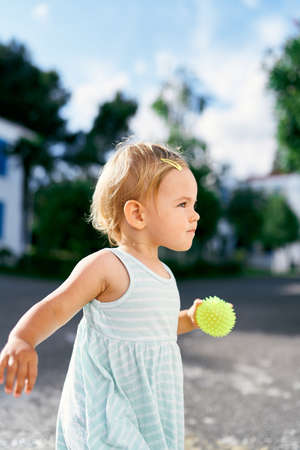 Little girl with a ball in her hand. Side view. Portrait